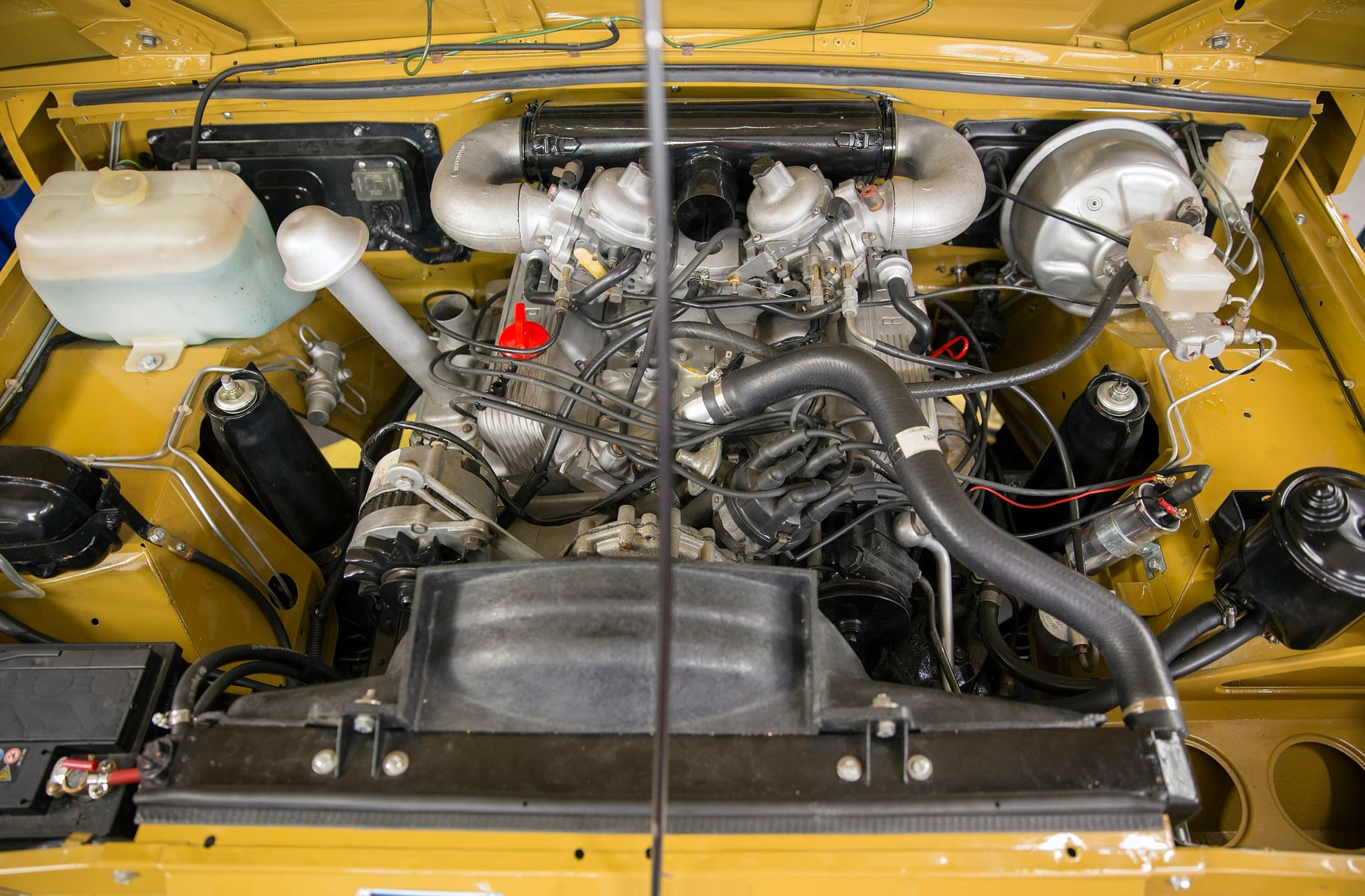 The aluminium Rover V8 with two carburettors in the yellow-painted engine bay of an early Range Rover.